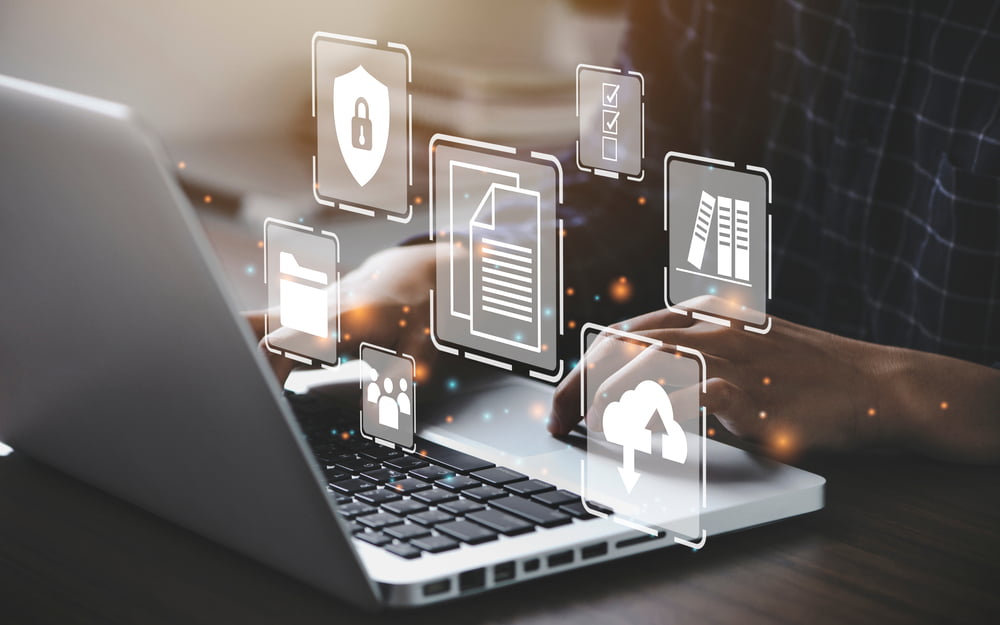 A close-up of hands typing on a laptop keyboard with floating digital icons representing security, documents, and cloud storage overlaid - it service provider A close-up of hands typing on a laptop keyboard with floating digital icons representing security, documents, and cloud storage overlaid - it service provider