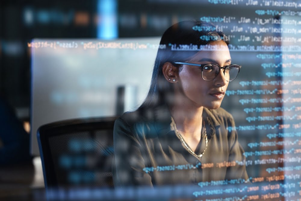 A woman in glasses works intently at a computer screen, with lines of code reflected in front of her - managed it services Riverside A woman in glasses works intently at a computer screen, with lines of code reflected in front of her - managed it services Riverside